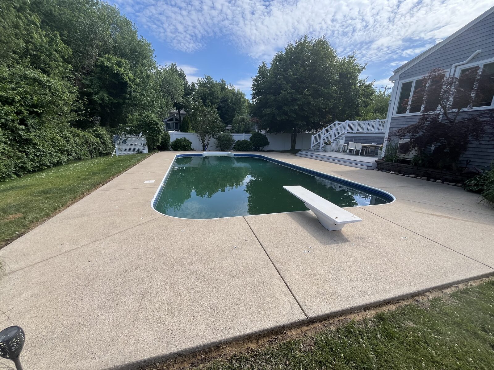 After pool deck cleaning in Marshfield MA by H2WOAH showing a bright, clean concrete pool deck and diving-board surround