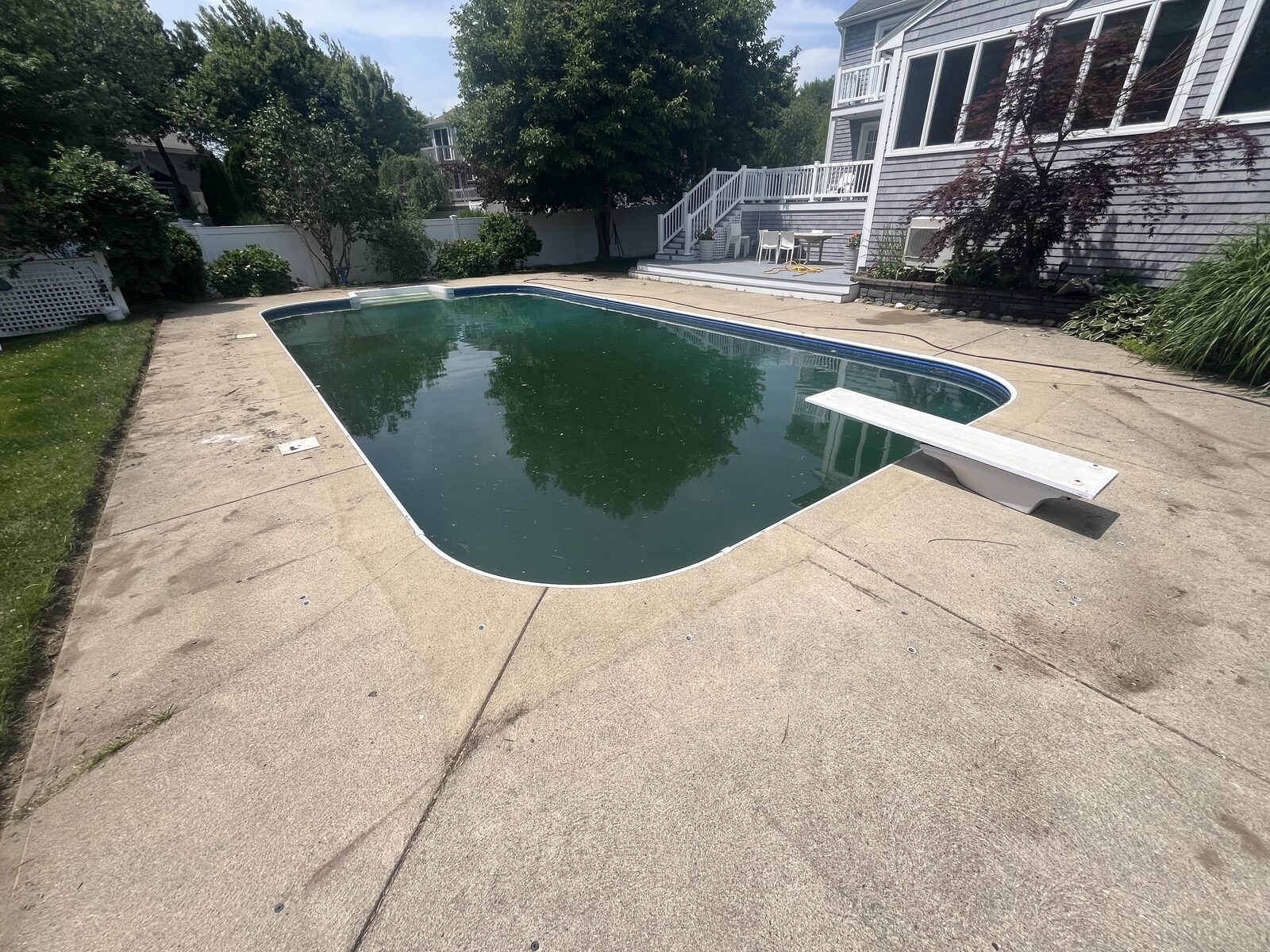 Before pool deck cleaning in Marshfield MA showing a dingy, dirty concrete pool deck with algae and grime