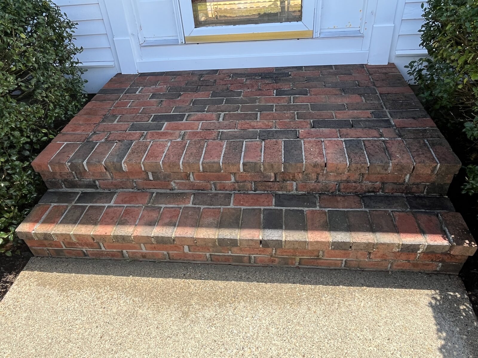 After careful soft washing old brick front steps in Marshfield MA showing clean red brick with the black mold safely removed and no damage to the delicate brick