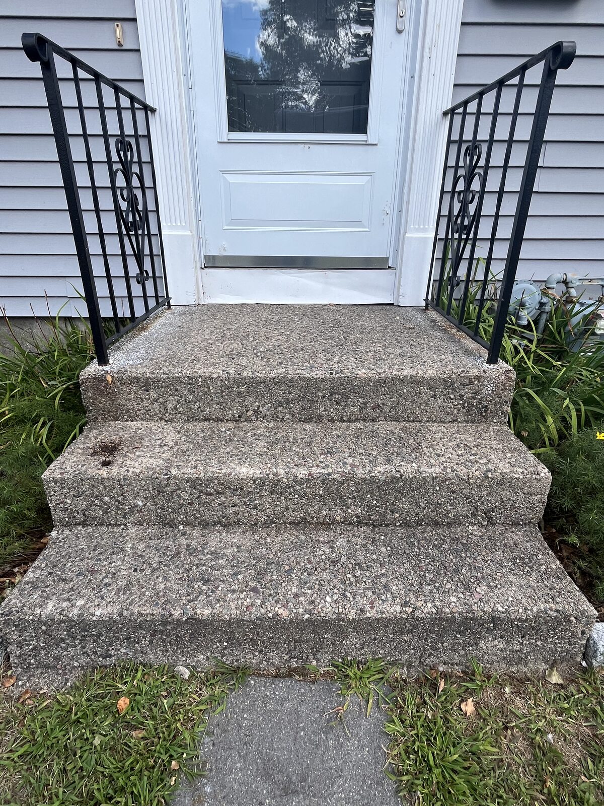 Before pressure washing concrete front steps in Attleboro MA showing dull gray exposed-aggregate steps with staining and organic grime between black iron railings