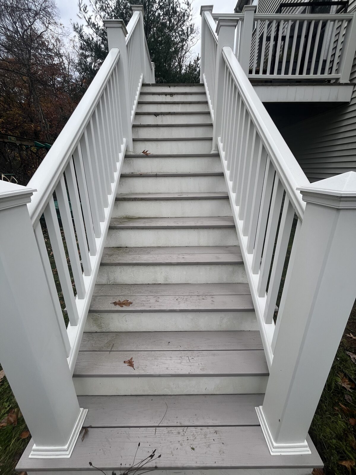 Before cleaning composite deck stairs in Duxbury MA showing organic buildup, dirt, and gray staining streaked across the steps between white railings