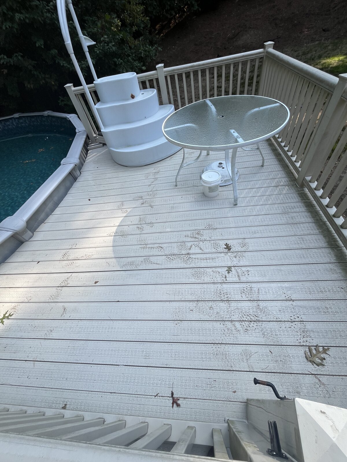 Before pressure washing a composite pool deck in Marshfield MA showing organic buildup, dirt, and dull gray staining across the deck boards beside an above-ground pool