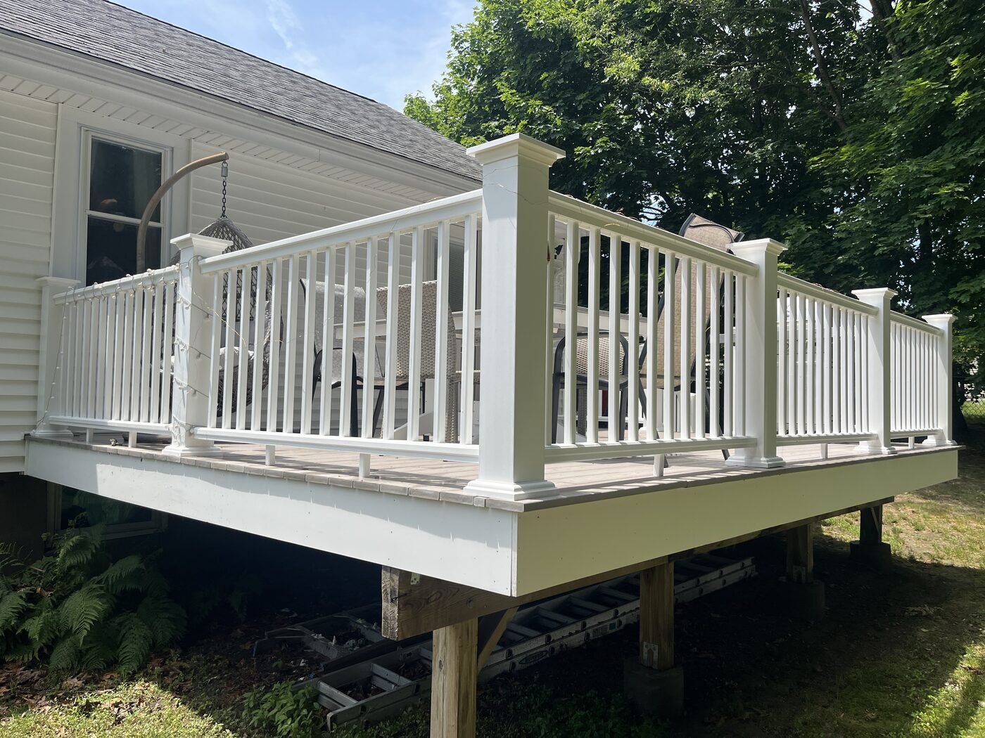 After cleaning a raised composite deck in Weymouth MA showing bright white railing and skirt board with the deck fully restored beside the home