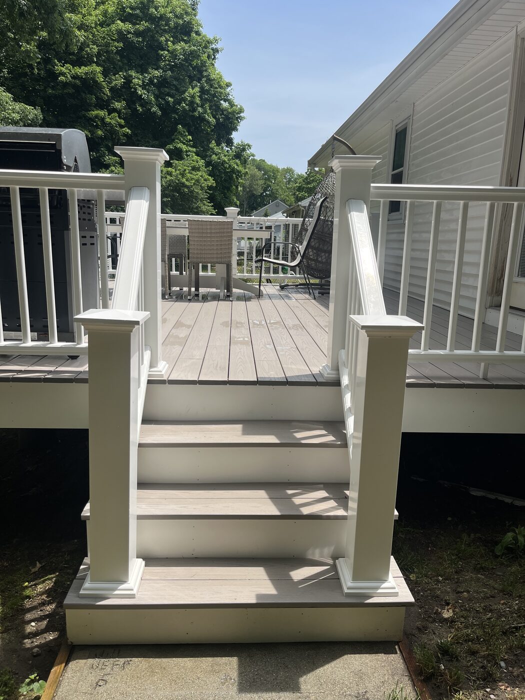 After cleaning composite deck steps in Weymouth MA showing bright white railing posts and clean light deck boards with the algae and grime removed