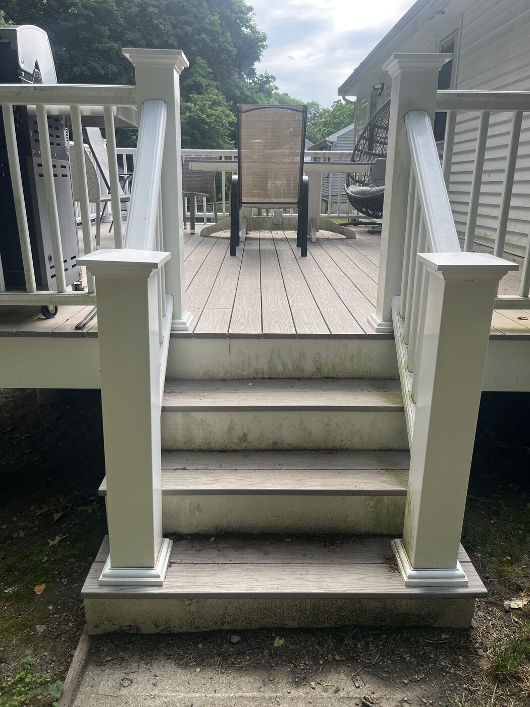 Before cleaning composite deck steps in Weymouth MA showing green algae and gray grime staining the white railing posts, steps, and deck boards