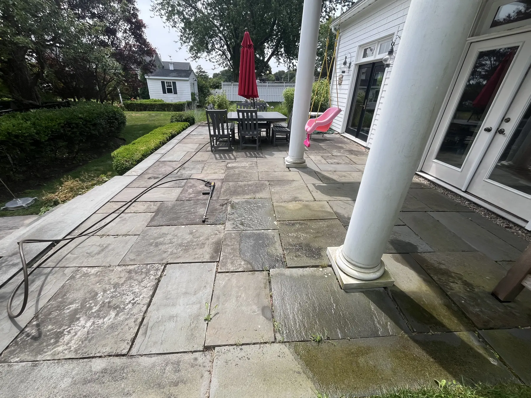 Bluestone patio cleaning in Plymouth MA, dark staining and organic buildup across patio stones before cleaning