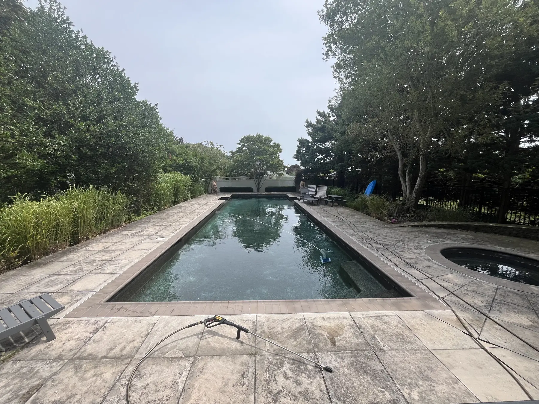 Pool deck cleaning in Plymouth MA, weathered buildup around an in-ground pool before pressure washing