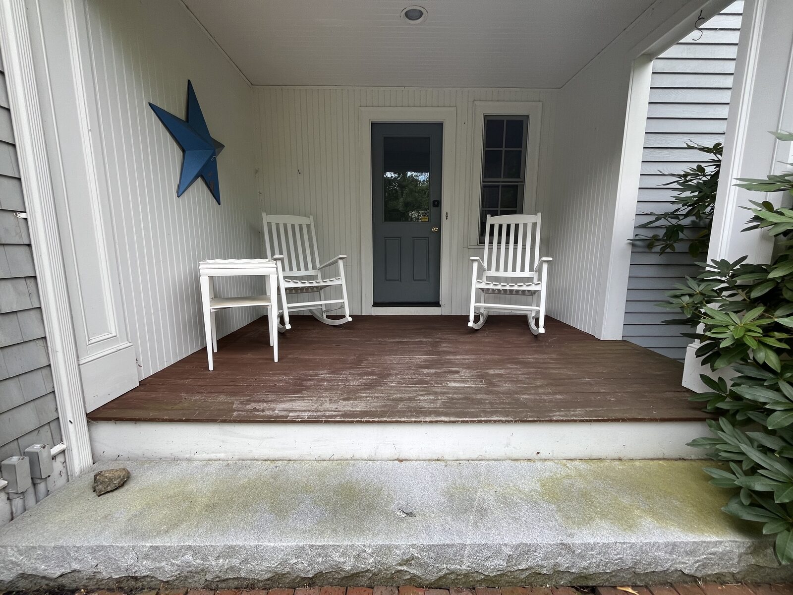 Before front porch soft washing in Duxbury MA showing organic buildup and mildew darkening the porch deck steps and siding