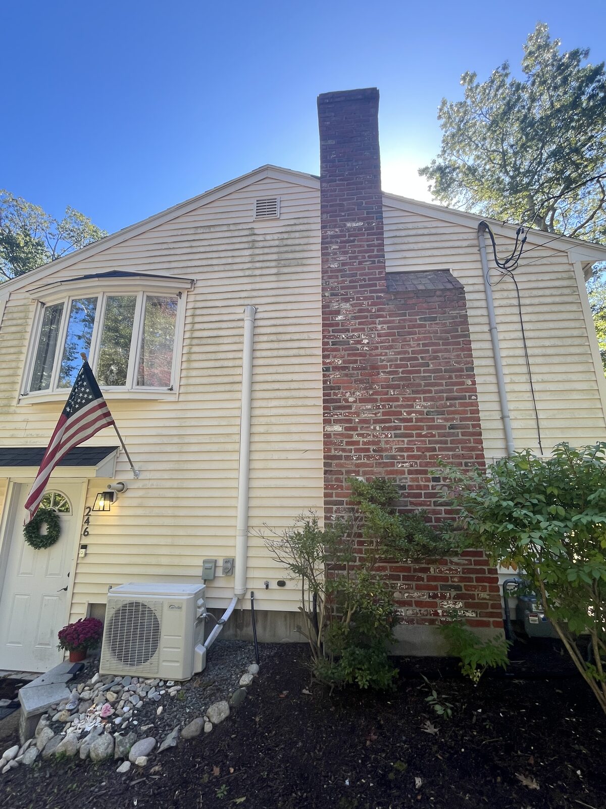 Before vinyl house wash in Hanover MA showing organic buildup and mildew streaking on the siding and a dirty brick chimney