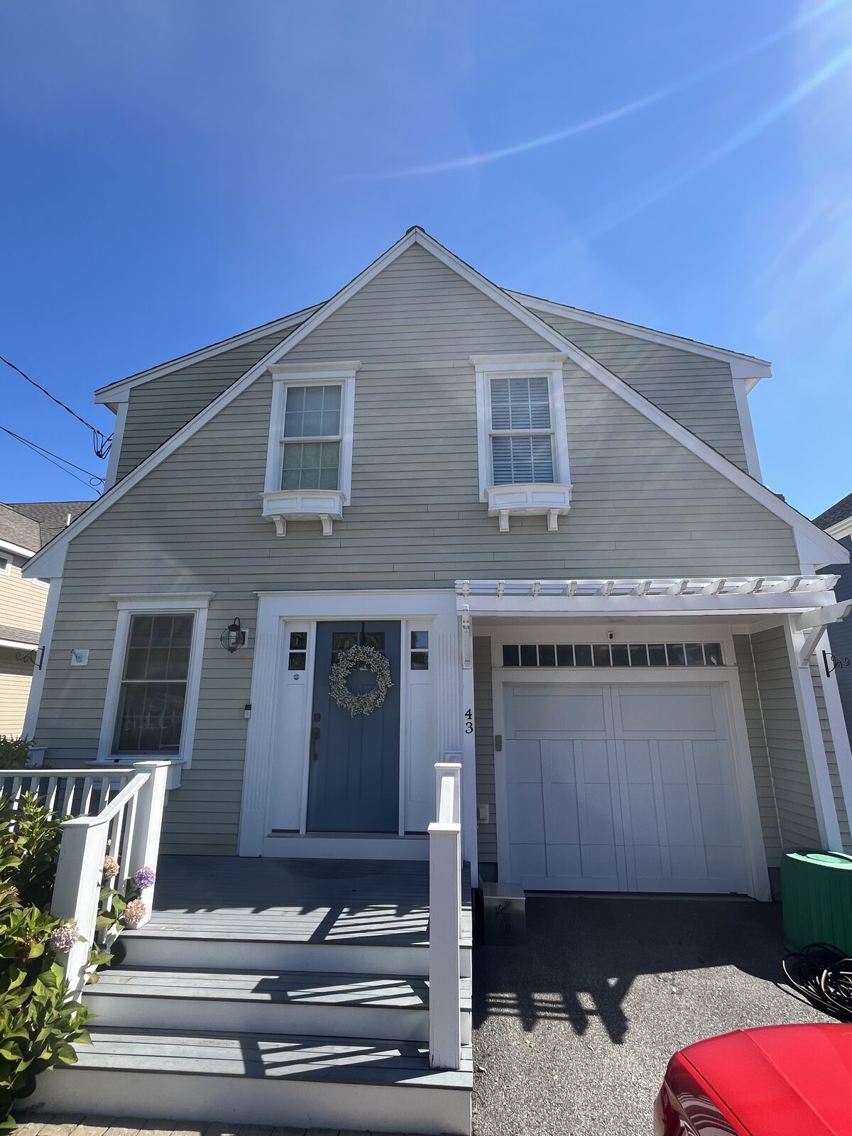 Front of a Hingham MA beach house with Hardie fiber-cement (hardy) siding after soft washing, showing clean sage clapboards, white trim, and pergola with organic buildup, salt residue, and green filth removed