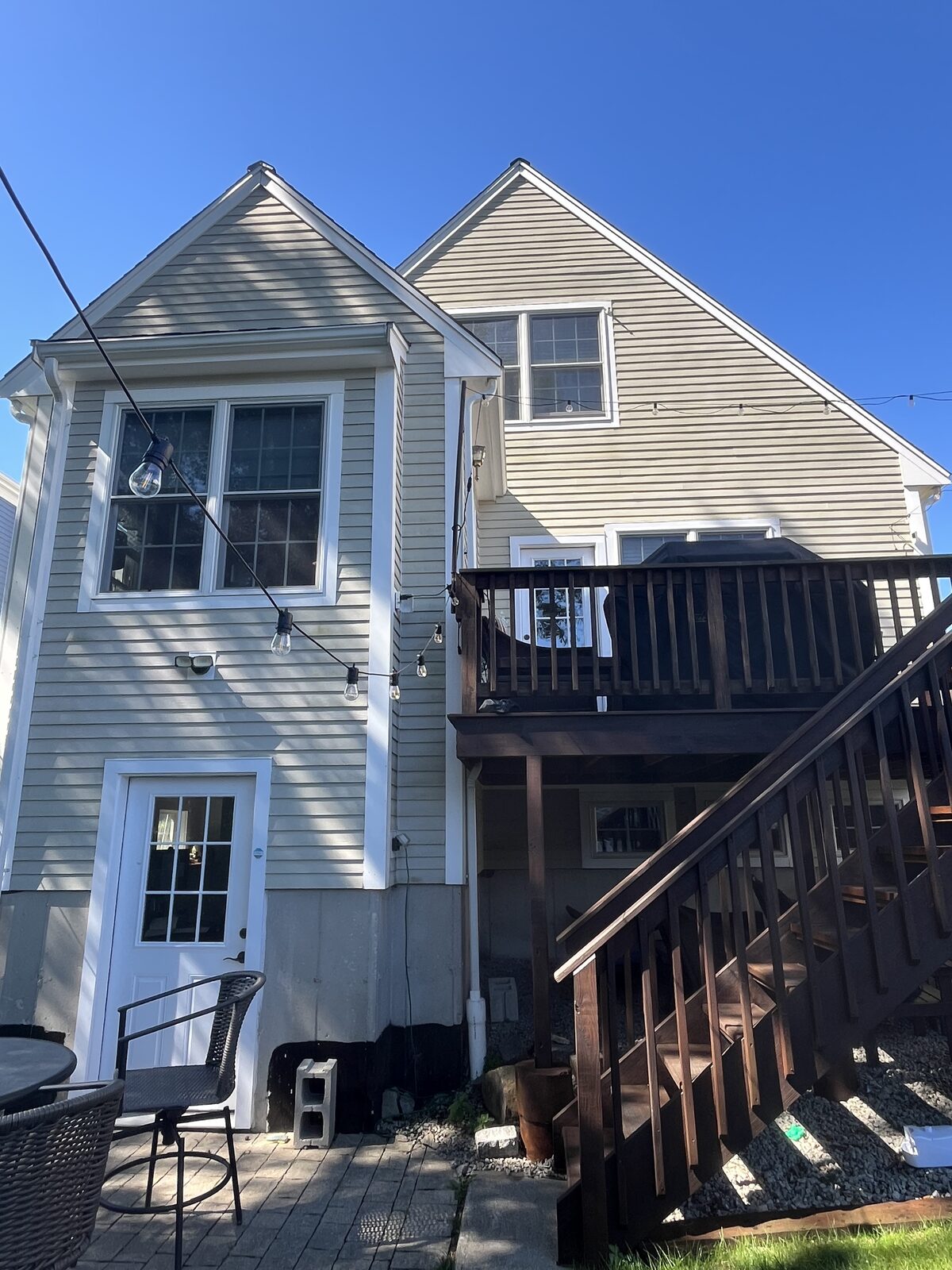 Rear of a Hingham MA beach house with Hardie (hardy) siding and a wood deck after soft washing, showing clean cream clapboards free of organic buildup, salt residue, and green algae