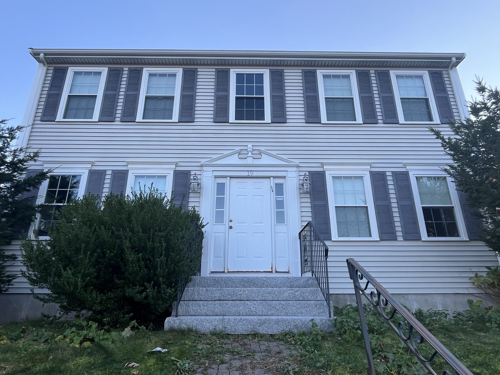 After soft wash vinyl house washing in Weymouth MA showing clean bright clapboard siding with years of green organic buildup removed