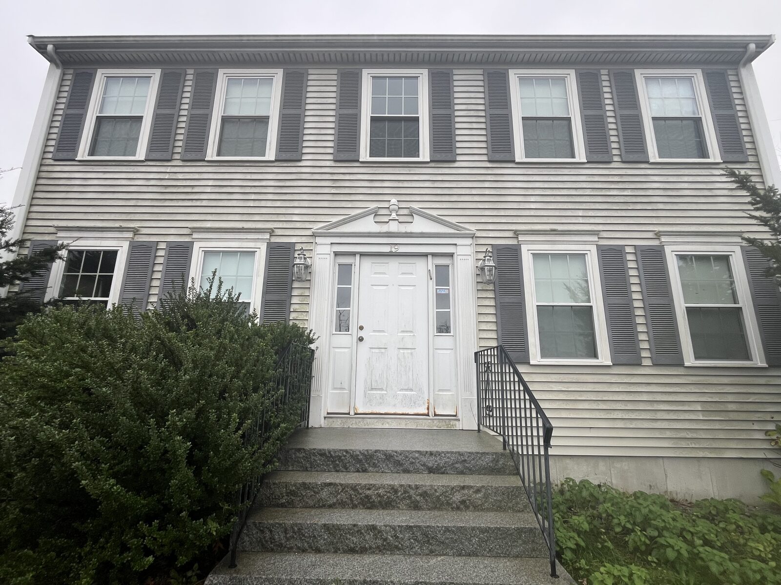 Before vinyl house washing in Weymouth MA showing years of green organic buildup and gray staining across the neglected clapboard siding of the home