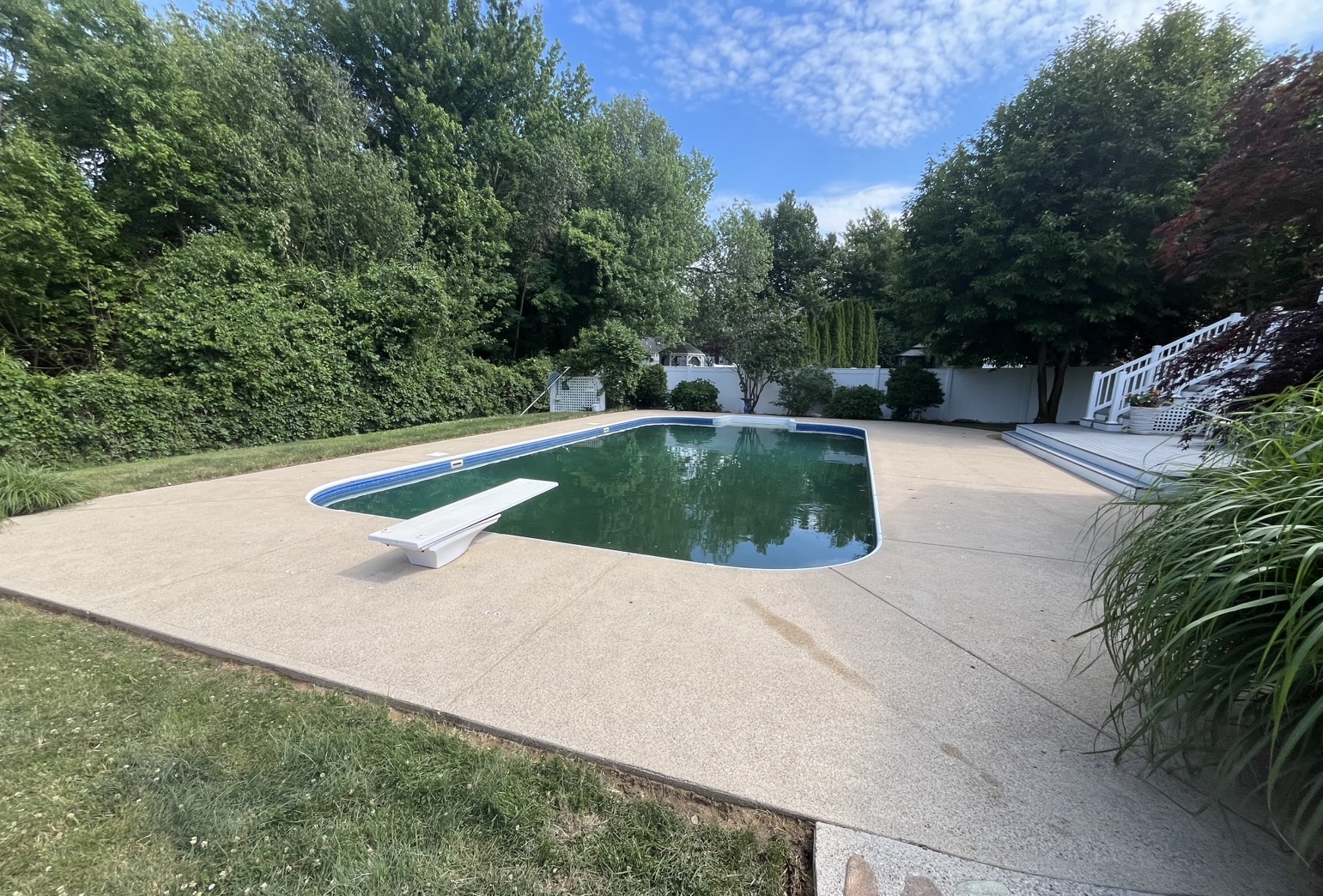 After aggregate pool deck cleaning in Marshfield MA by H2WOAH Exterior Cleaning showing a clean exposed-aggregate deck around a diving-board pool
