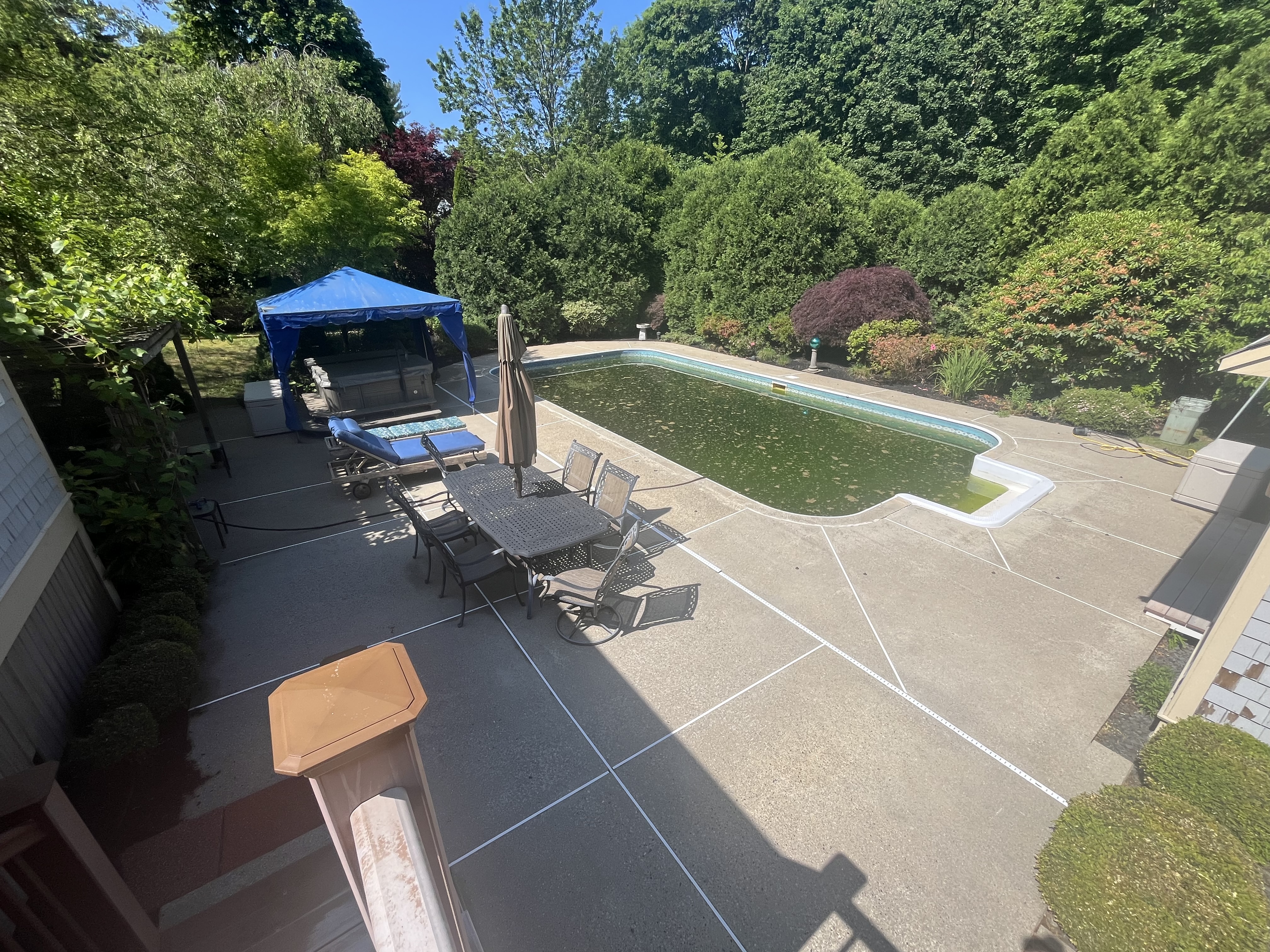 After concrete pool deck cleaning in Marshfield MA by H2WOAH Exterior Cleaning showing a bright clean patio around an in-ground pool
