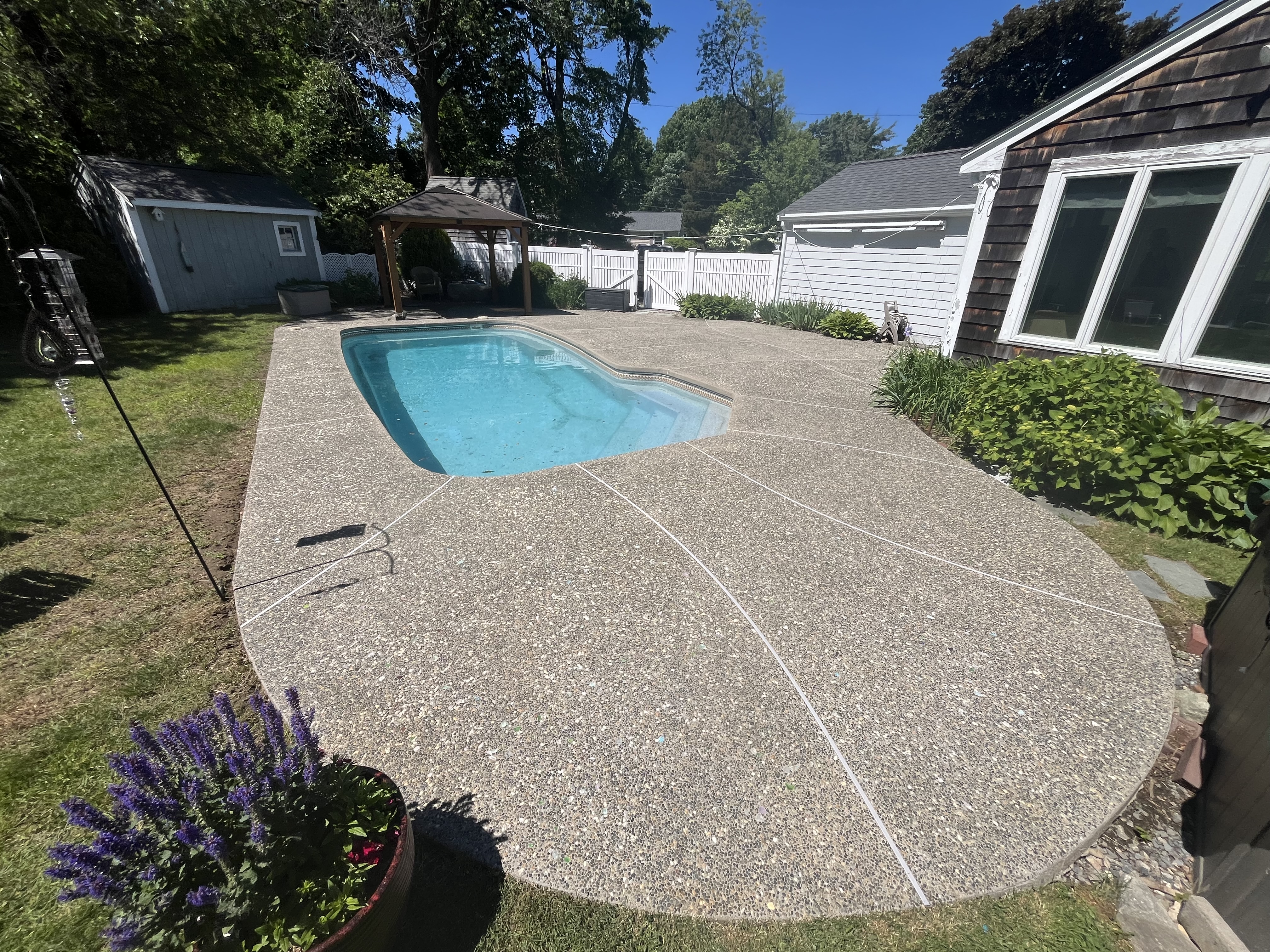 After aggregate pool deck cleaning in Marshfield MA by H2WOAH Exterior Cleaning showing a clean exposed-aggregate deck around a freeform pool